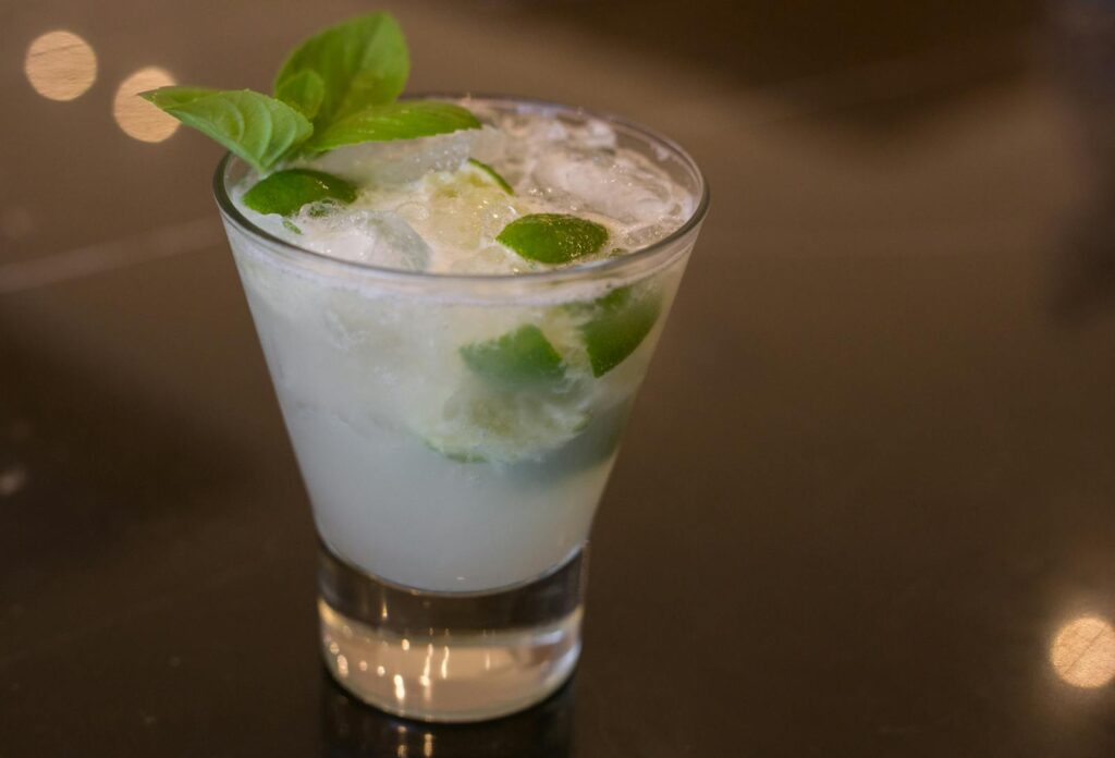 Cool and refreshing lime cocktail with fresh basil garnish in a glass, perfect for summer.