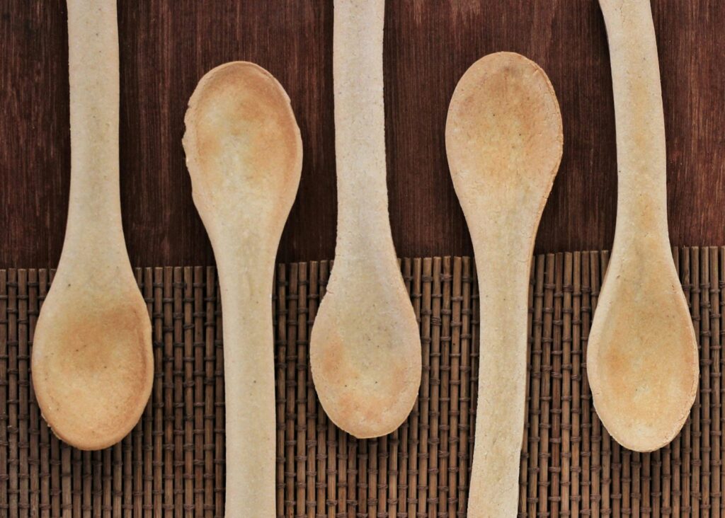 Five spoons lined up in a row on a mat