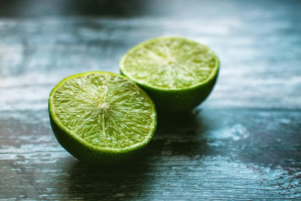 Vibrant green lime halves on a rustic wooden surface, showcasing fresh citrus texture.