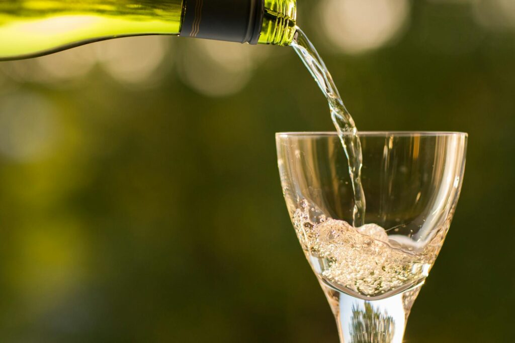 Close-up of wine being poured into a glass with a green bokeh background.