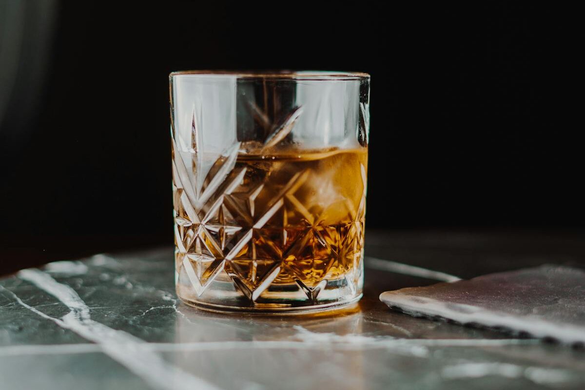 A classic glass of whiskey on a marble table with a dark background.