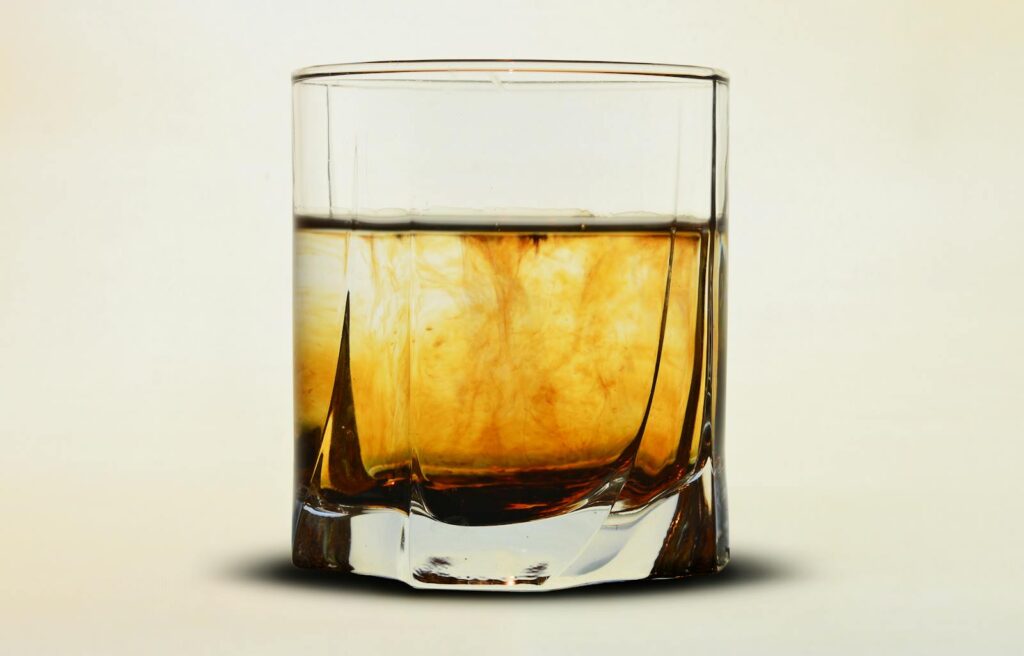 Close-up of an amber whiskey in a glass with a soft neutral backdrop, perfect for beverage themes.