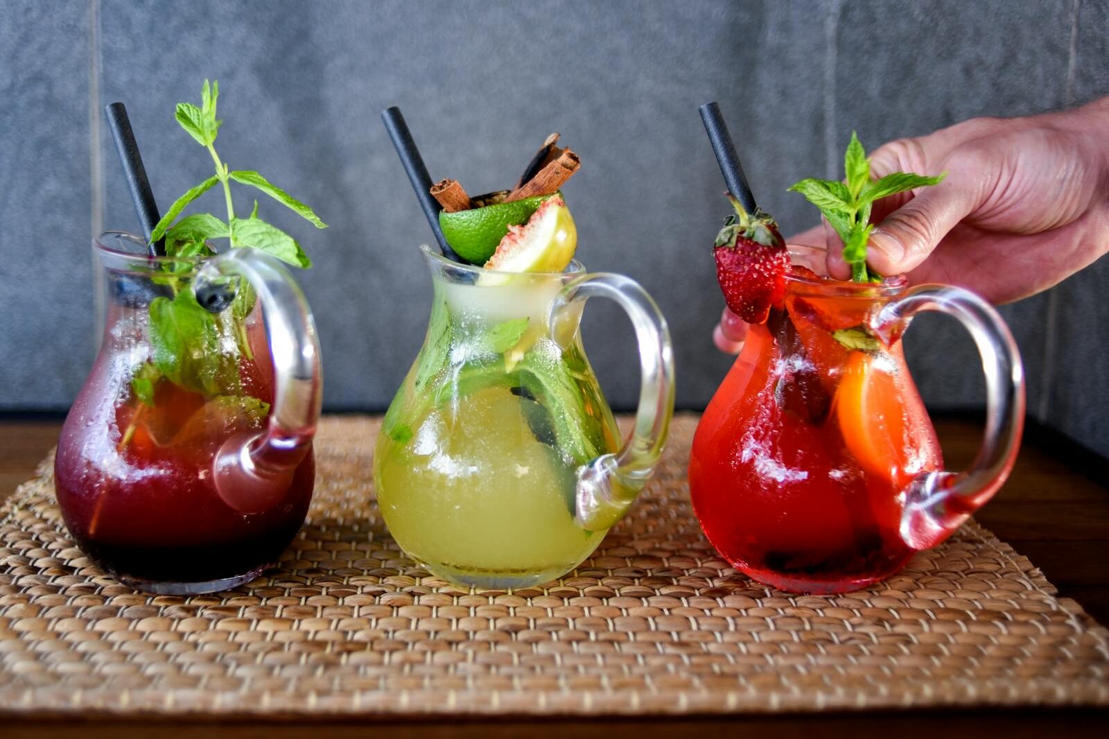 Colorful fruit cocktails served in glass mugs with fresh garnishes.