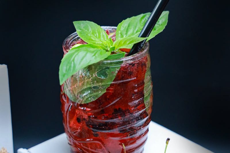 A refreshing berry drink with mint leaves, served in a glass with cherries on the side.