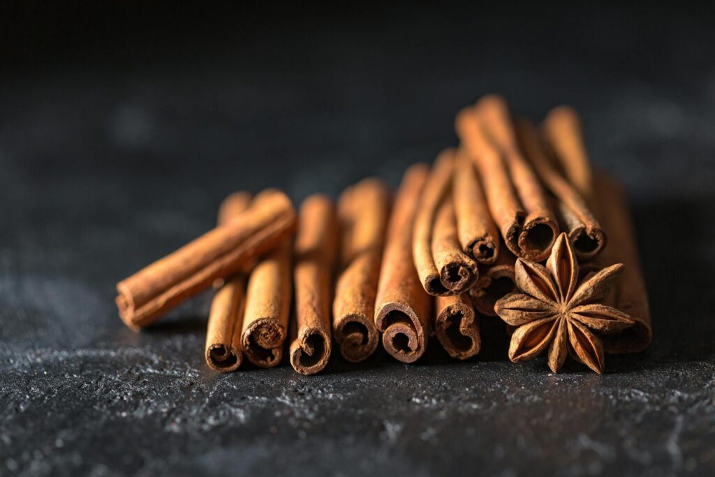 Close-up of cinnamon sticks and star anise on a dark, textured surface, evoking warm, aromatic flavors.