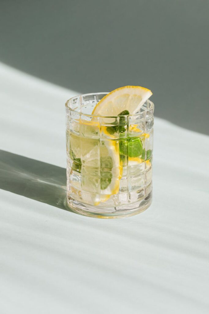 A refreshing lemon mint beverage served in a clear glass on a sunlit surface.