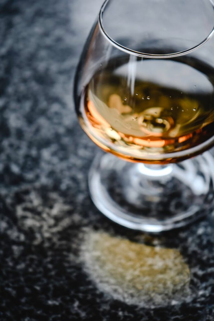 Close-up of an amber whiskey in a glass on a granite counter, highlighting texture and color contrast.