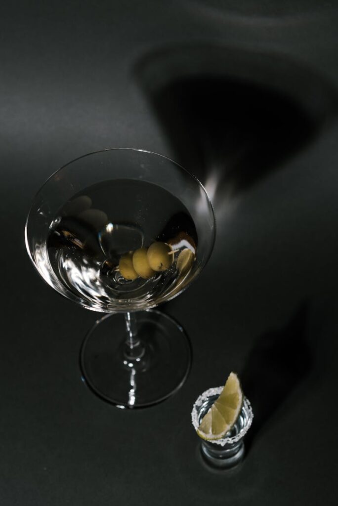 A sophisticated martini glass with olives, paired with a lemon garnish on a dark background.