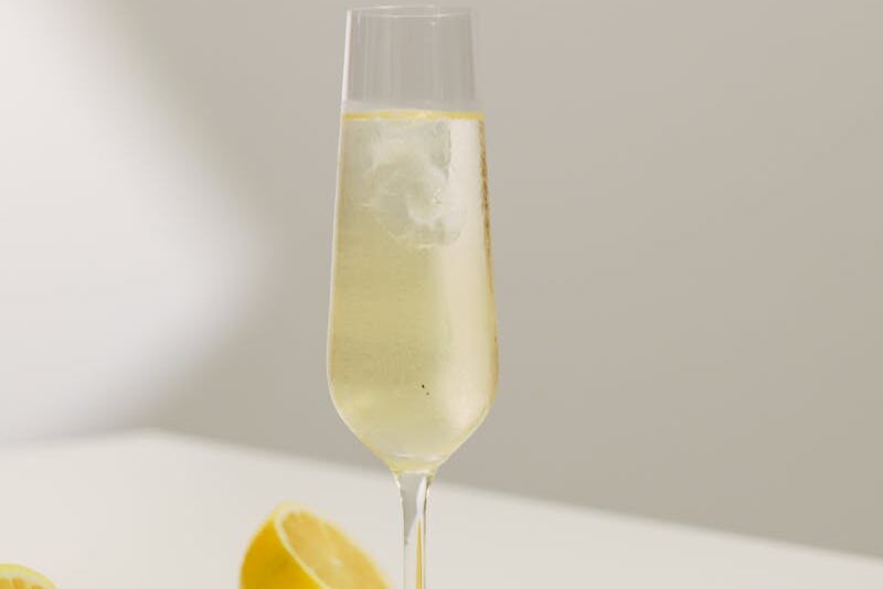 Champagne glass with fresh lemon slices on a white table, capturing a refreshing still life.